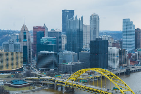 a yellow bridge over a river in front of a city