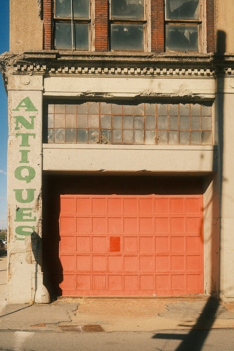 Old building with antiques sign and red garage door