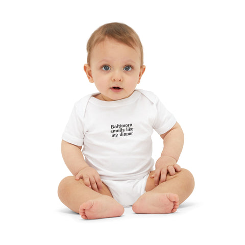 Baby in white onesie with 'Baltimore smells like my diaper' text, perfect for funny and comfortable babywear.