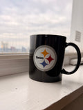 Black mug with a Pittsburgh Steelers sports team logo on a windowsill