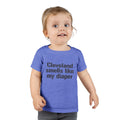 Toddler in heather blue T-shirt with bold black text 'Cleveland smells like my diaper,' a humorous kids fashion piece.